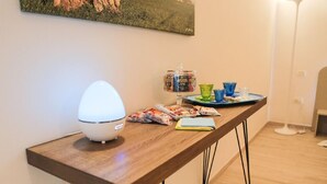 A wooden table with a white lamp, a glass jar with snacks, and a tray with blue and green cups. - Ailanthus Holiday Suites (Polignano a Mare)