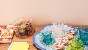 A table with a jar of cookies, a glass pitcher, and various packaged snacks. - Ailanthus Holiday Suites (Polignano a Mare)