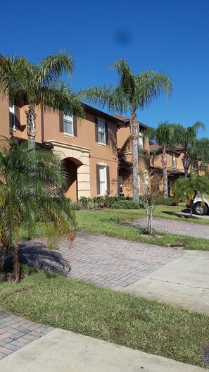 Un edificio residencial con un camino de ladrillo y palmeras.