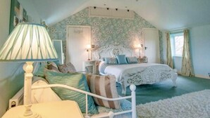Een slaapkamer met een bed, nachtkastjes, een lamp en een zacht vloerkleed.