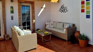 Eine Terrasse mit Korbmöbeln, einem Tisch mit gelben Schalen und einem Blumentopf.