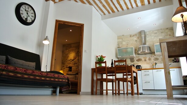 Een moderne woonkamer met een bank, een eettafel met stoelen, een keuken met een stenen muur en een houten plafond.