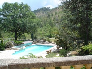 A swimming pool surrounded by lush greenery and a stone wall. - Villa in Drôme Provençale with heated pool and SPA (Eygaliers)