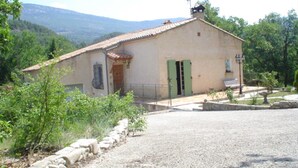 Un petit bâtiment d’un seul étage, avec un toit recouvert de tuiles, une porte verte et un petit balcon.