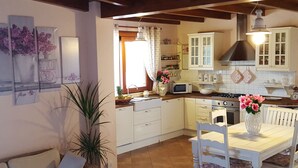A kitchen with white cabinets, a microwave, a stove, and a dining table with chairs. - BEAUTIFUL VILLA WITH PRIVATE POOL, 150 METERS FROM THE SEA (QUARTU SANT'ELENA ,CAPITANA)