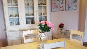 A dining area with a yellow table, white chairs, a white cabinet with glass doors, and a hanging light fixture. - BEAUTIFUL VILLA WITH PRIVATE POOL, 150 METERS FROM THE SEA (QUARTU SANT'ELENA ,CAPITANA)
