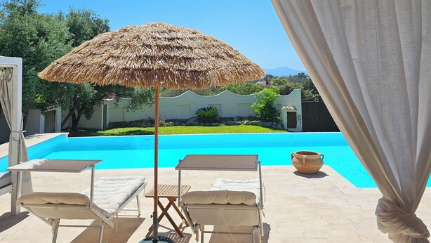 A poolside area with a thatched umbrella, two lounge chairs, and a view of a clear blue pool. - BEAUTIFUL VILLA WITH PRIVATE POOL, 150 METERS FROM THE SEA (QUARTU SANT'ELENA ,CAPITANA)