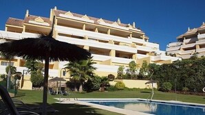 Ein Hotel mit Pool, Liegestühlen und einem Strohdachschirm.