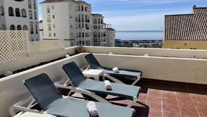 Eine Dachterrasse mit Liegestühlen und Blick auf das Meer.