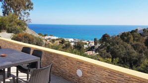 A terrace with a table and chairs overlooking a coastal view.