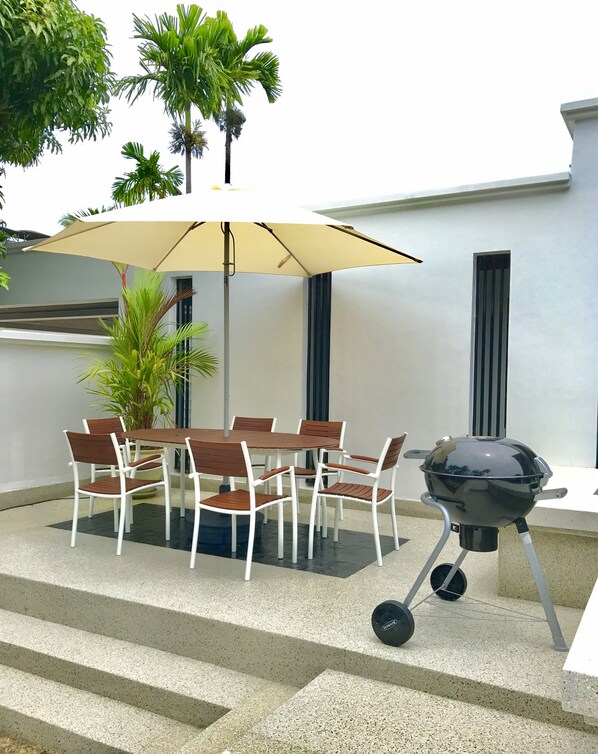 An outdoor patio with a table and chairs, a barbecue grill, and a large umbrella. - Fabulous Villa, private pool & garden, excellent service, Surin & Bangtao Beach (Surin)