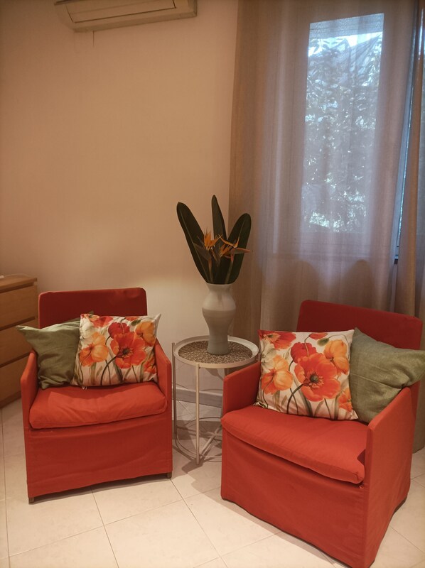 A living room with two red sofas, a small round table, and a potted plant.