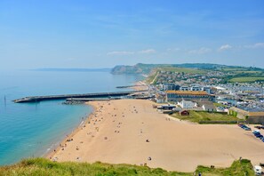 A coastal town with a sandy beach, a pier, and a marina.
