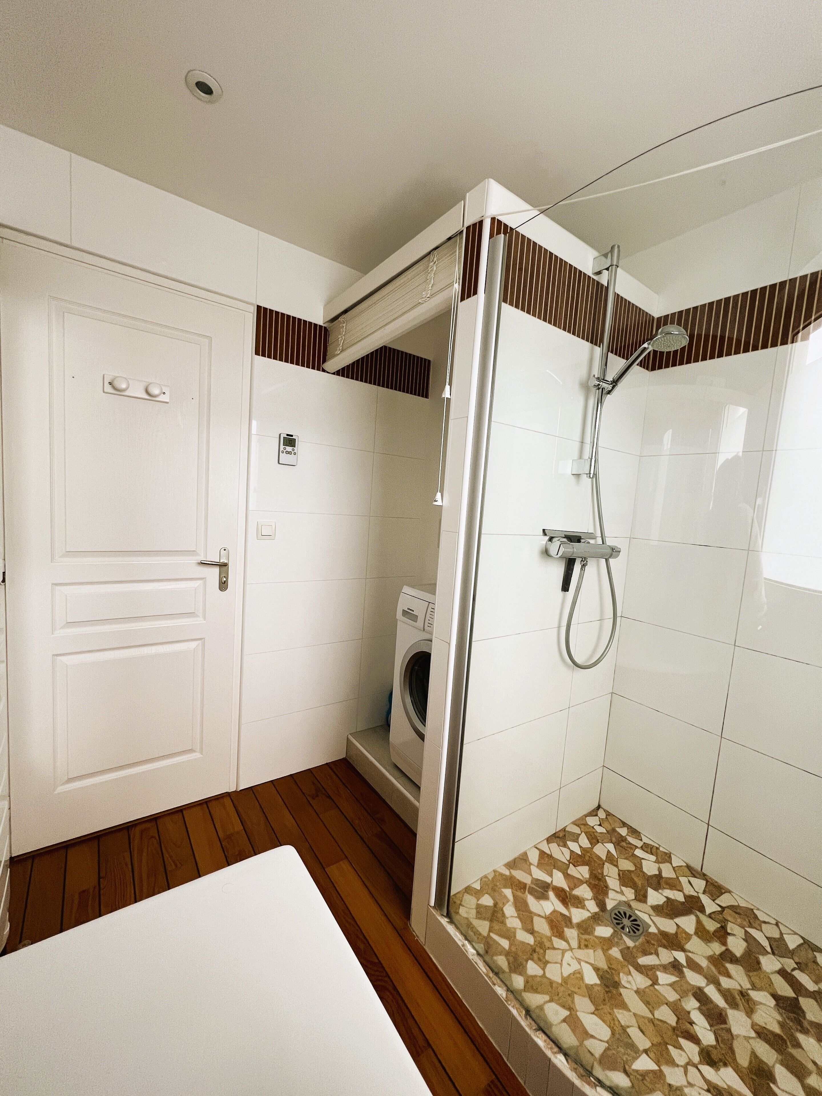 Une petite salle de bain comprenant une douche, un lave-linge et des toilettes.
