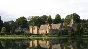 A castle-like building with a moat, surrounded by lush greenery and trees.
