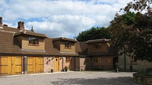 A traditional brick building with multiple wooden doors and a gravel driveway.