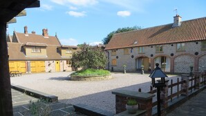 A courtyard with a gravel path, a wooden bench, and a stone wall with a lantern.