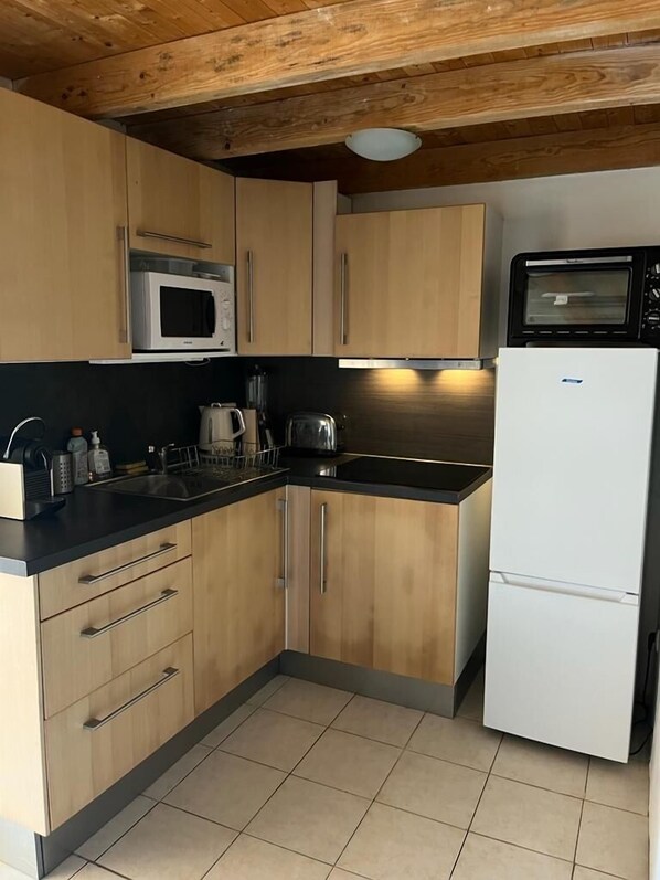 A compact kitchen with wooden cabinets, a microwave, a toaster, and a refrigerator. - mini-villa with A/C in tree-planted residence - swimming pool, seaside, Corsica (santa maria poggio)