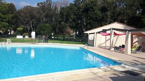 Una piscina con area coperta e lettini.