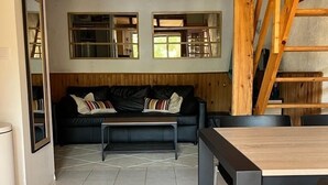 Un soggiorno con soffitto in legno, un divano, un tavolo da pranzo e sedie.