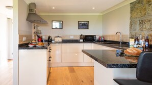 Una cucina moderna con mobili bianchi, un piano di lavoro in granito e una parete decorata con pietra.