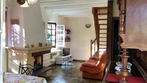 A cozy living room with a fireplace, a dining table, and a comfortable seating area. - In the center of Périgord  Noir (SARLAT 20 Km)- LE COUX et BIGAROQUE.  Périgourdine house with  swimming pool, beautiful panorama on valley, on property of 6 ha. (Coux Et Bigaroque-Mouzens)
