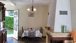 A dining area with a table set for four, a chandelier, and a fireplace. - In the center of Périgord  Noir (SARLAT 20 Km)- LE COUX et BIGAROQUE.  Périgourdine house with  swimming pool, beautiful panorama on valley, on property of 6 ha. (Coux Et Bigaroque-Mouzens)