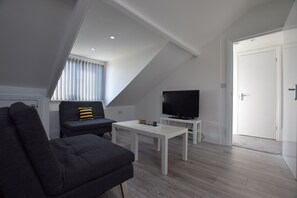 Een moderne woonkamer met een bank, een televisie en een witte tafel.