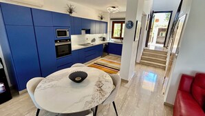 A modern kitchen with blue cabinets, a white countertop, and a marble dining table. - 'Villa Xenia' HG 25  Play golf, tennis or relax in the spa (Aphrodite Hills)