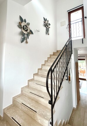 A staircase with beige steps and a black railing, leading to a room with a door and a window. - 'Villa Xenia' HG 25  Play golf, tennis or relax in the spa (Aphrodite Hills)