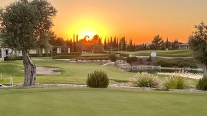 A golf course with a sunset view, well-maintained grass, sand bunkers, and a pond. - 'Villa Xenia' HG 25  Play golf, tennis or relax in the spa (Aphrodite Hills)