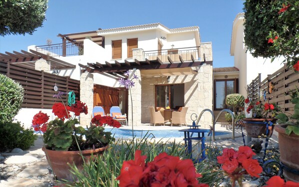A modern house with a pool, outdoor seating, and potted plants. - 'Villa Xenia' HG 25  Play golf, tennis or relax in the spa (Aphrodite Hills)