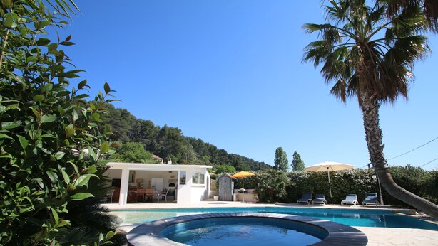 A swimming pool with a hot tub, surrounded by lush greenery and a white building with outdoor seating. - Beautiful villa with garden, swimming pool and jacuzzi close to all amenities (La Farlède)