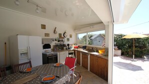A kitchen with a dining table, chairs, and a refrigerator. There is a window providing natural light and a view of the outside. - Beautiful villa with garden, swimming pool and jacuzzi close to all amenities (La Farlède)