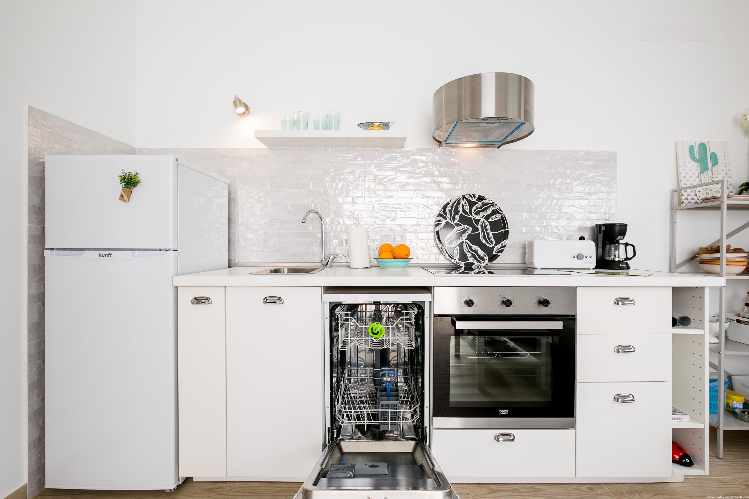 A modern kitchen with a built-in dishwasher, oven, and a coffee machine.