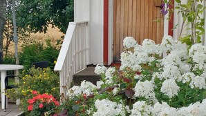 Ett hus med en trädörr, vita ytterväggar och en veranda med trappsteg som leder till entrén.