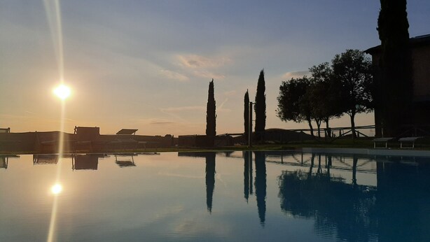 A serene pool area with clear reflections, surrounded by tall cypress trees and a distant building. - Casa di Campagna Colline Senesi San Giovanni in Poggio - app. Twilight Siena (Monteroni d'Arbia)