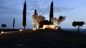 A building with a prominent central structure, surrounded by tall cypress trees and smaller trees, set against a clear sky. - Casa di Campagna Colline Senesi San Giovanni in Poggio - app. Twilight Siena (Monteroni d'Arbia)