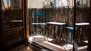 An outdoor seating area with wooden tables and chairs, a glass partition, and a view of the cityscape. - CHARMING STUDIO AT THE CATHEDRAL. (STRICTLY TWO PEOPLE) (València)
