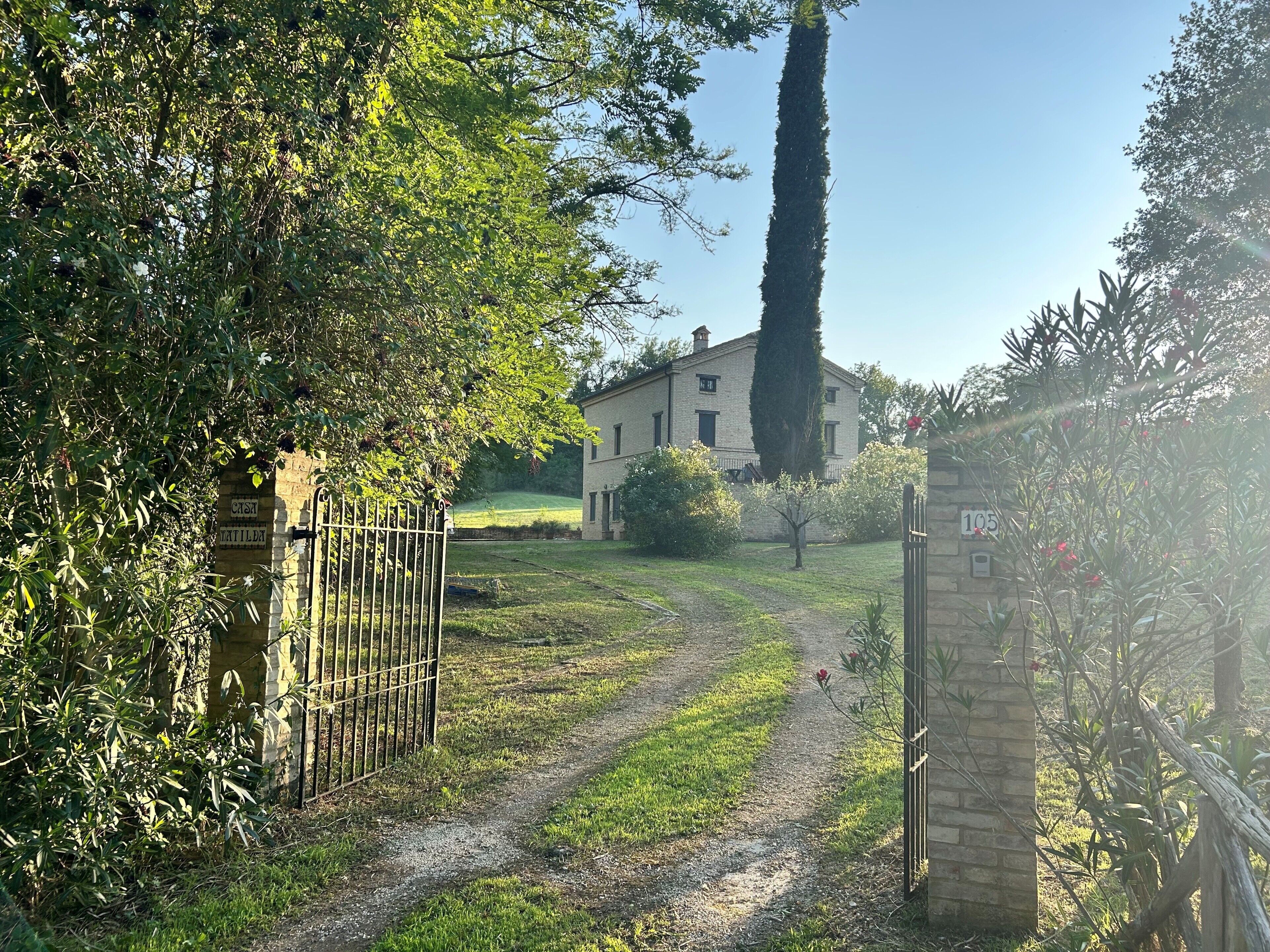 Un sentiero che conduce a un edificio con un muro in pietra e un cancello in metallo.