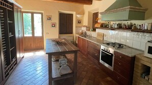 A kitchen with a central island, wooden cabinets, a stove, and a large window. - Large Farmhouse in peaceful location with large pool letting fast. (Penna San Giovanni)