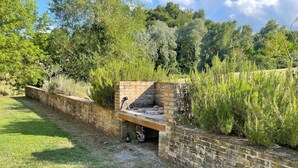 Un espace barbecue extérieur en briques, avec un banc en pierre et un gril.