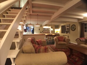 En hyggelig stue med trappe, spiseplads og køkken.