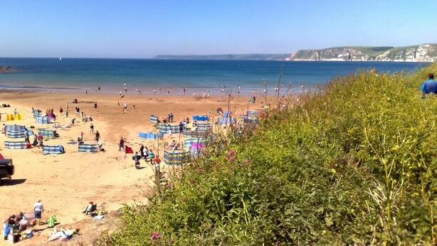 Une plage avec des gens, des tentes et un ciel dégagé.