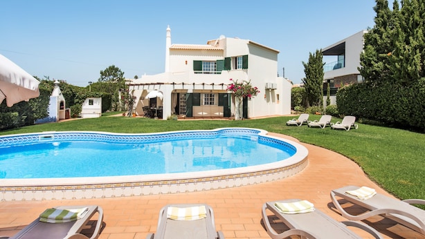 Una casa de dos pisos con piscina y mobiliario exterior.