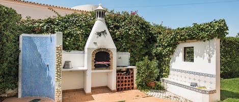 A patio area with a barbecue grill, a water feature, and a small seating area.
