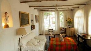 A cozy room with a bed, a table with a plaid tablecloth, a chair, and a window with curtains. - Historic patrician country house with exceptional location (Carmona)