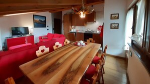 Un salon chaleureux avec une table à manger en bois, des canapés rouges et un téléviseur.