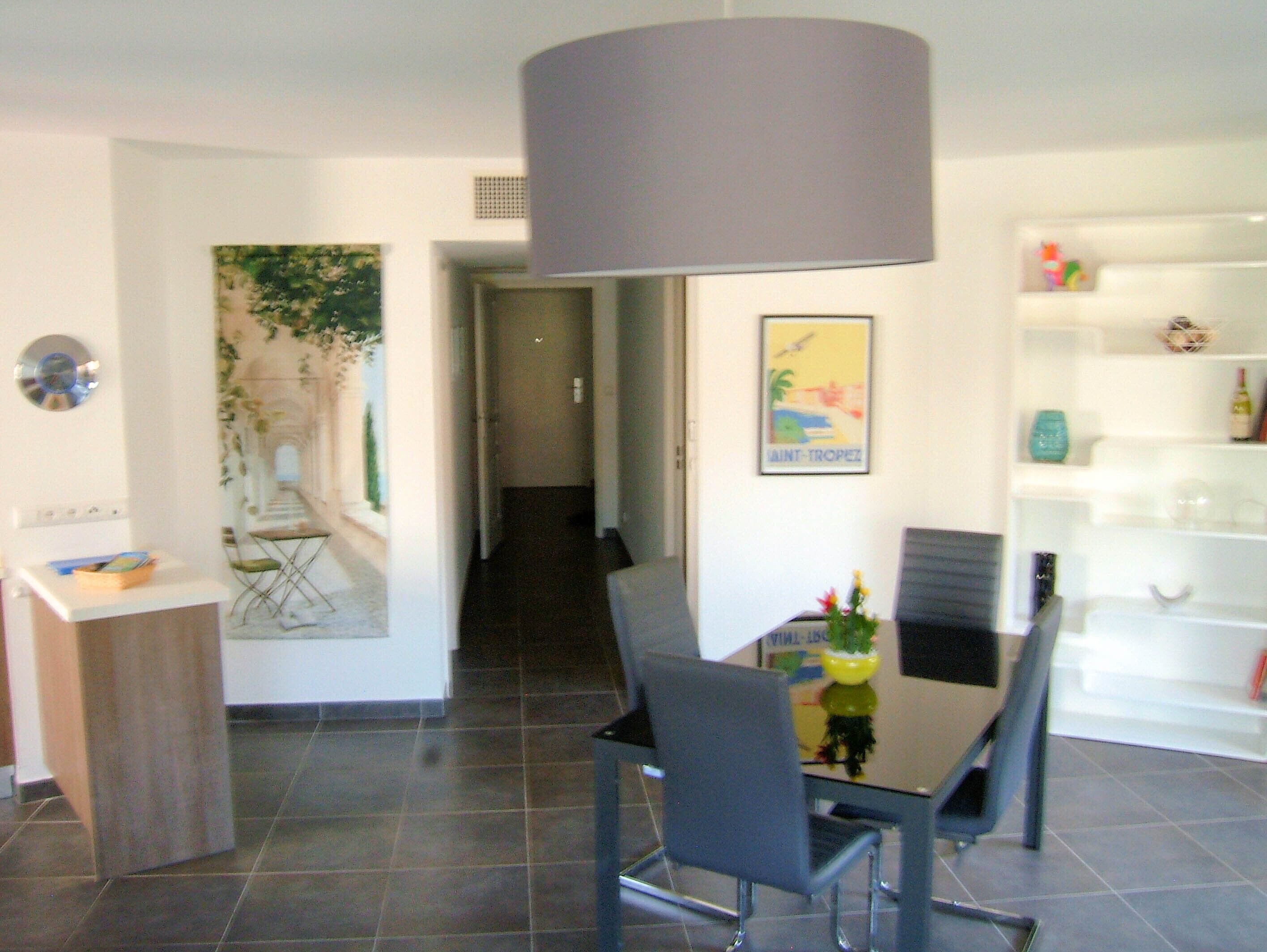 A modern dining area with a table and chairs, a wall-mounted lamp, and a poster.