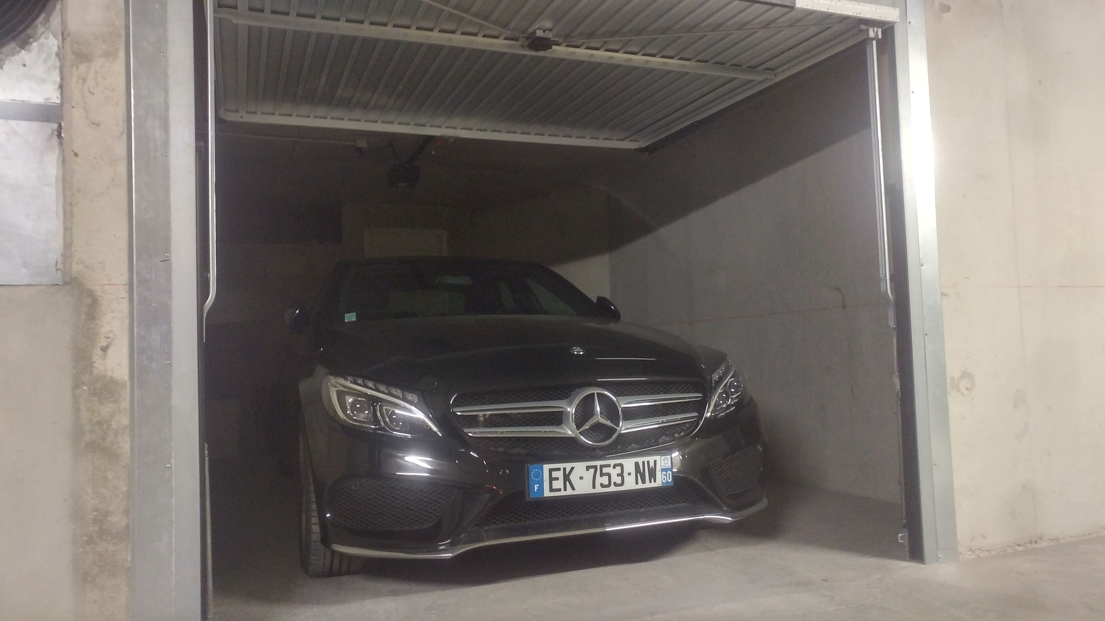 Ein schwarzer Mercedes-Benz steht in einer Garage, das Kennzeichen ist sichtbar.